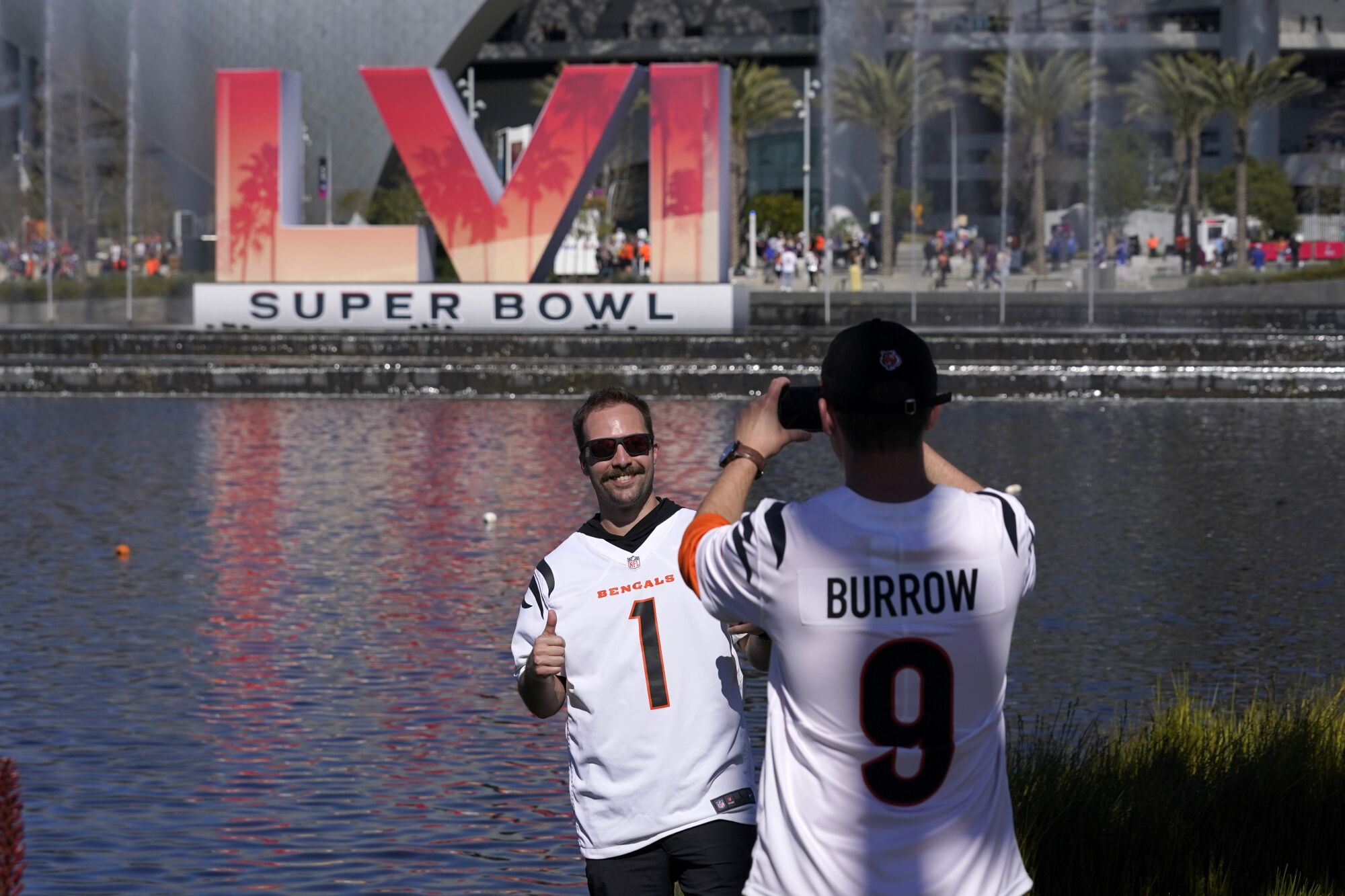 Cincinnati Bengals fans take pictures in front of big Super Bowl LVI letters and a body of water 