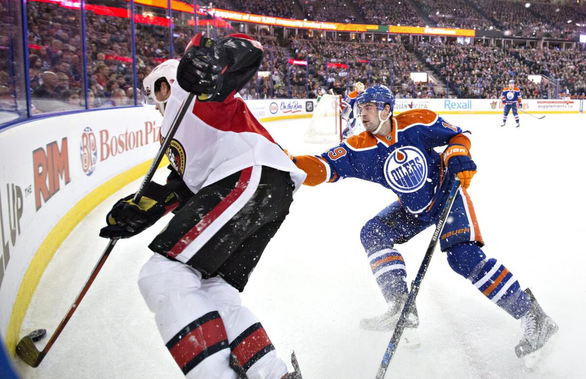 Oilers defenseman Justin Schultz (19) battles for the puck with the Senators' Bobby Ryan, left, during the first period on Feb. 23.