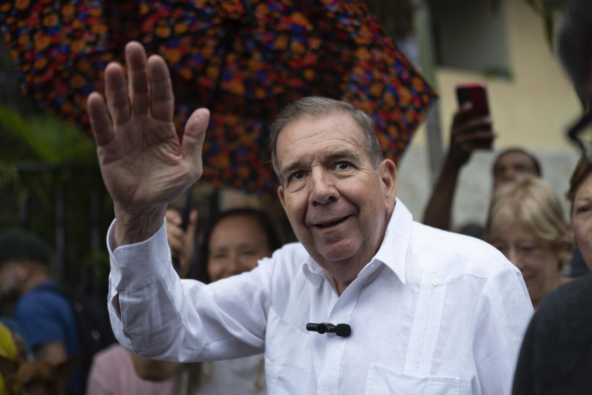 Edmundo Gonzalez Urrutia stands among a crowd and waves. 