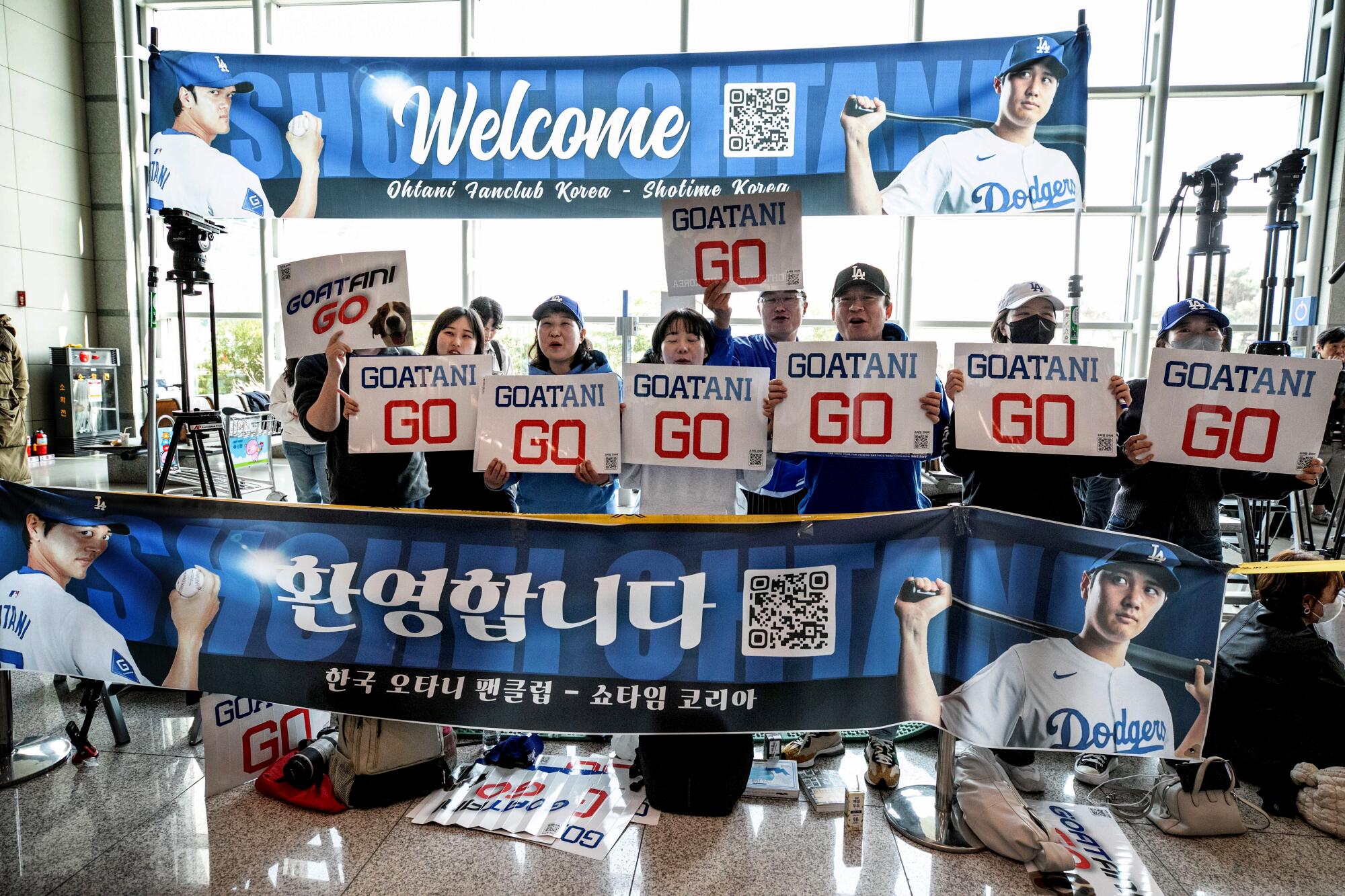 Ohtani fans line up with banners and handheld signs reading "Goatani Go."