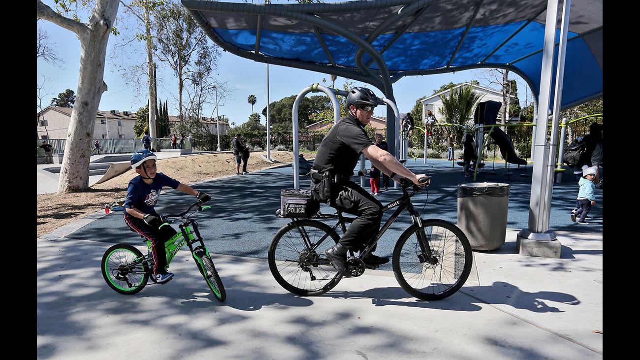 A young boy follows Glendale Police officer Steve Kiszis on his bicycle at the Glendale Police Department's inaugural "Shields on the Field" event, where residents got to know local law-enforcement officials through conversations, playing basketball, taking part in a skate competition or learning about crime prevention or bike safety at Palmer Park in Glendale on Saturday, Feb. 24, 2018.