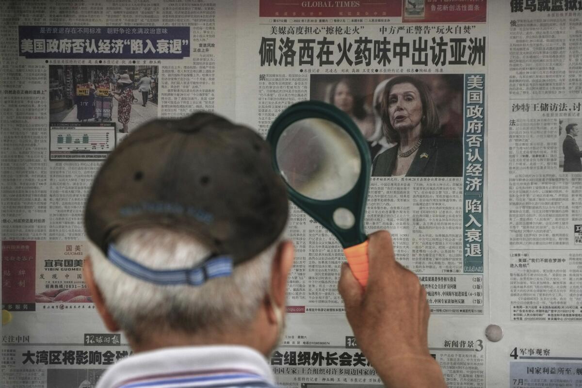 A man in Beijing uses a magnifying glass to read a newspaper article about House Speaker Nancy Pelosi.