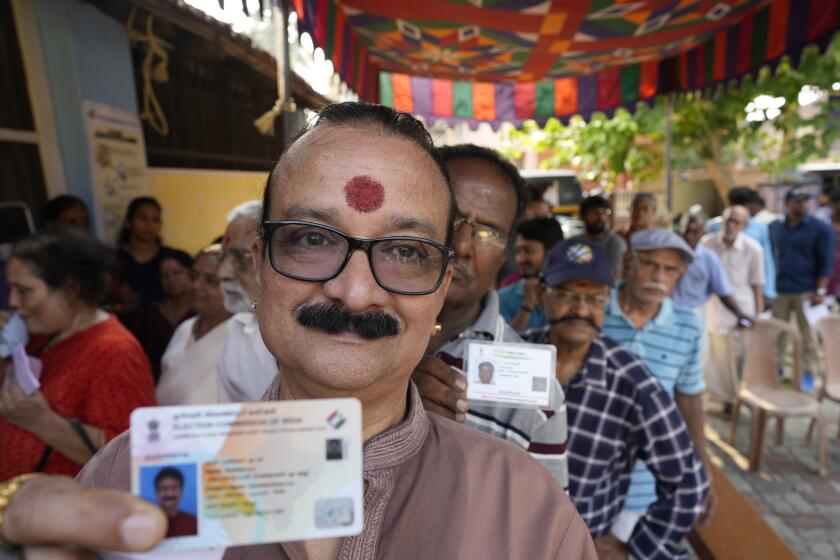 Un hombre muestra su tarjeta de votación mientras hace fila para participar en la segunda fase de las elecciones generales cerca de Palakkad, en el estado de Kerala, en el sur de India, el 26 de abril de 2024. (AP Foto/Manish Swarup)