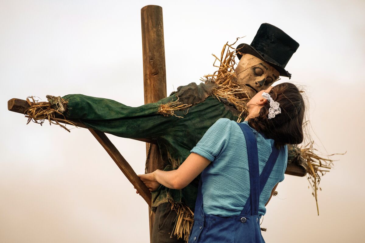 A young woman embraces a scarecrow in the movie "Pearl."