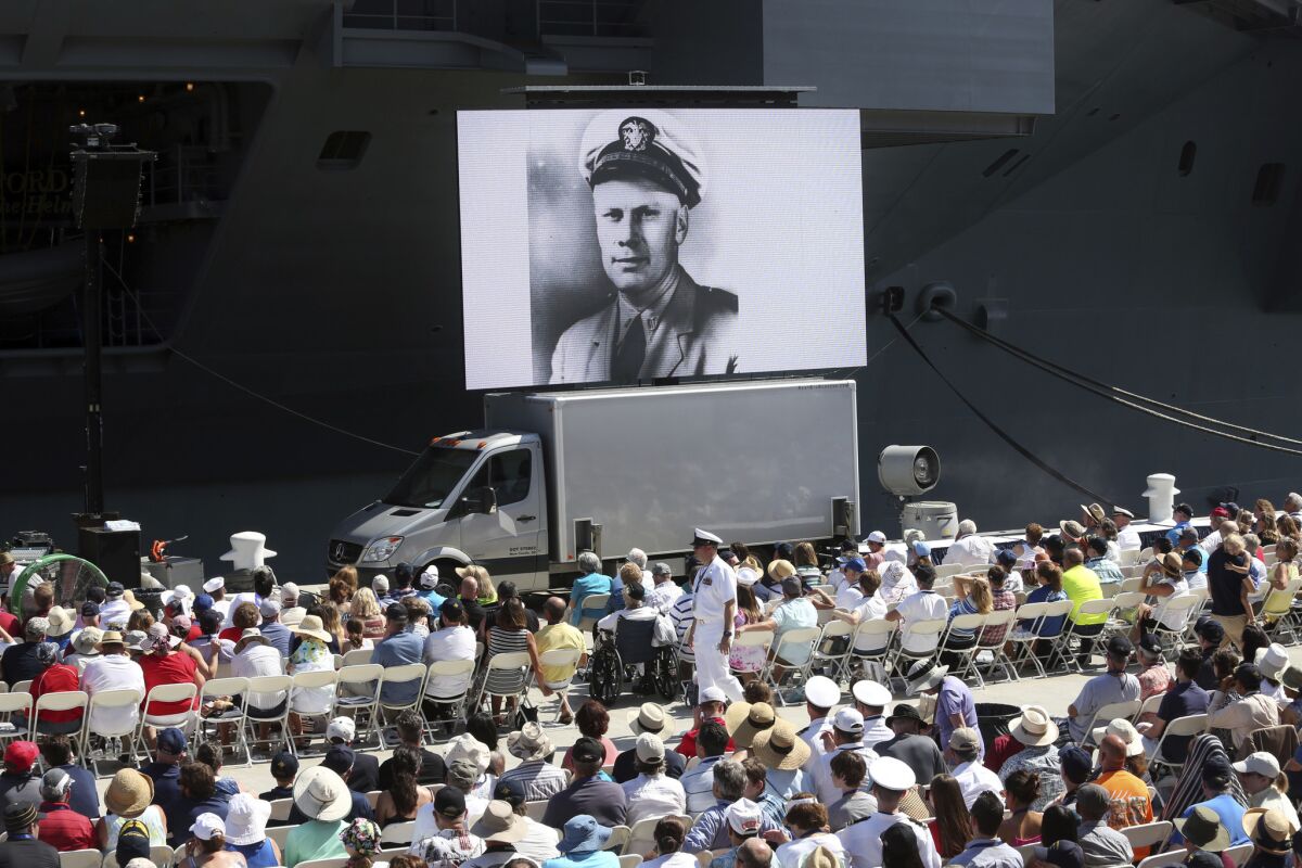 An image of Gerald R. Ford as a naval officer is shown on a video screen during the commissioning ceremony at Naval Station Norfolk.