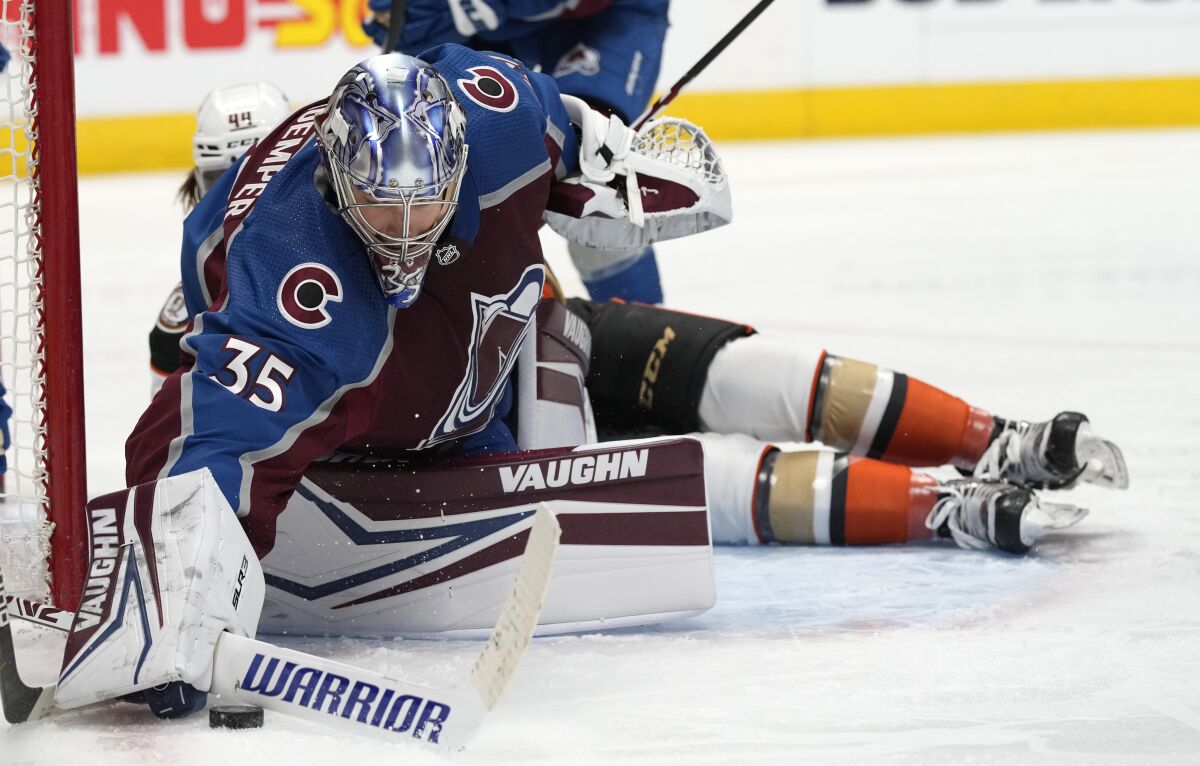 Colorado Avalanche goaltender Darcy Kuemper, front, clears the puck after stopping a shot against the Anaheim Ducks in the second period of an NHL hockey game Sunday, Jan. 2, 2022, in Denver. (AP Photo/David Zalubowski)