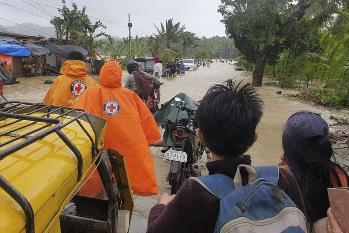En esta foto distribuida por la Cruz Roja Filipina, voluntarios y vecinos cruzan un camino inundado debido al tifón Conson en la aldea de Usab, Filipinas, martes 7 de setiembre de 2021. (Cruz Roja Filipina via AP)