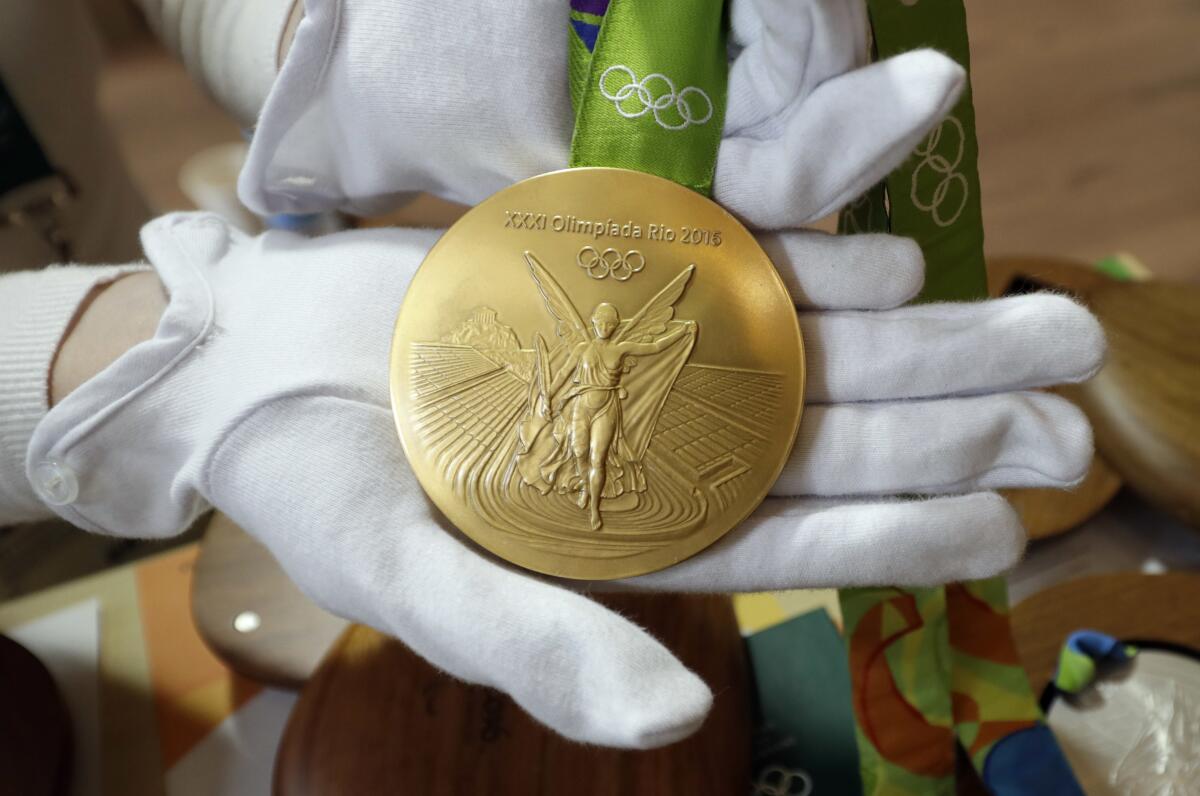 A person holds a gold medal.