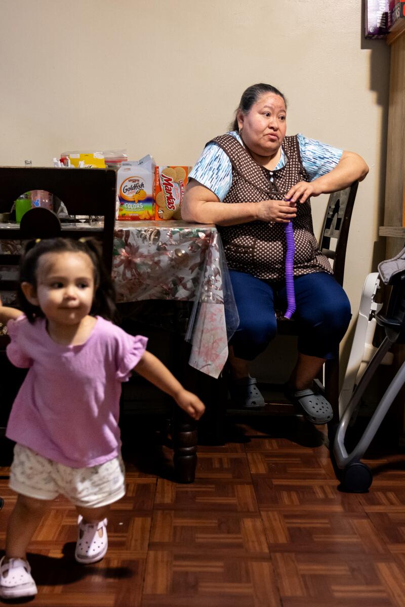 Grandparents sit at their table as a granddaughter holds her grandfather's hand