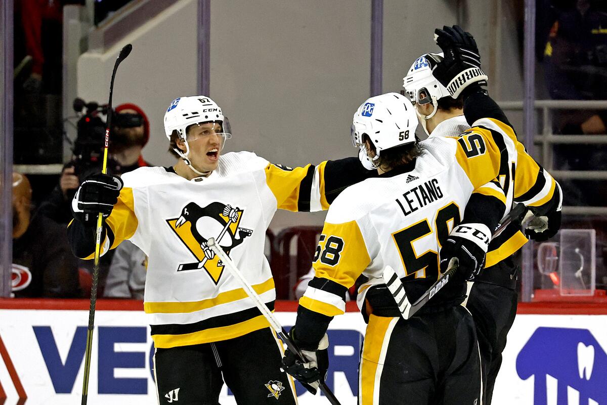 Pittsburgh Penguins' Rickard Rakell, left, celebrates after his goal with teammates Evgeni Malkin, right, and Kris Letang (58) during the second period of an NHL hockey game against the Carolina Hurricanes in Raleigh, N.C., Sunday, Dec. 18, 2022. (AP Photo/Karl B DeBlaker)