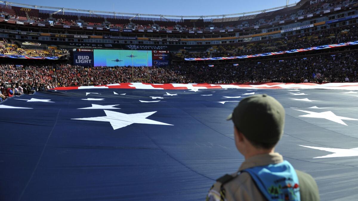 A Boy Scout holds the American flag during a flyover prior to an NFL football game between the Atlanta Falcons and Washington Redskins on Nov. 4 in Landover, Md.