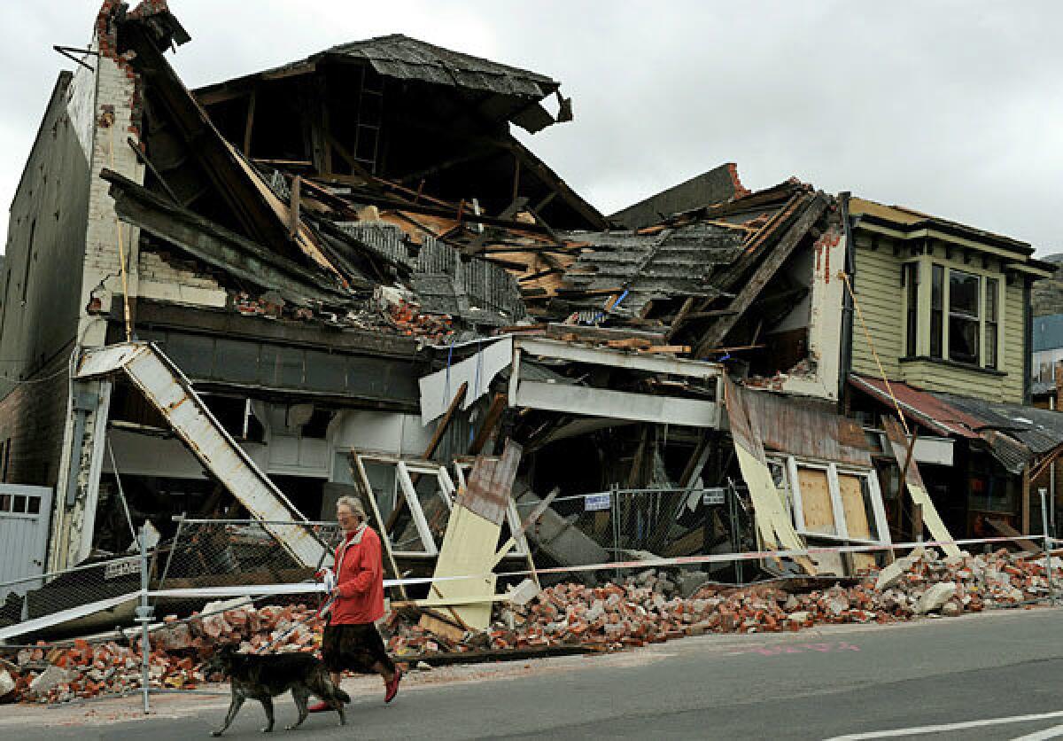 A woman walks her dog past the ruins of a store in the port town of Lyttelton, New Zealand, which was the epicenter of the 6.3 earthquake.