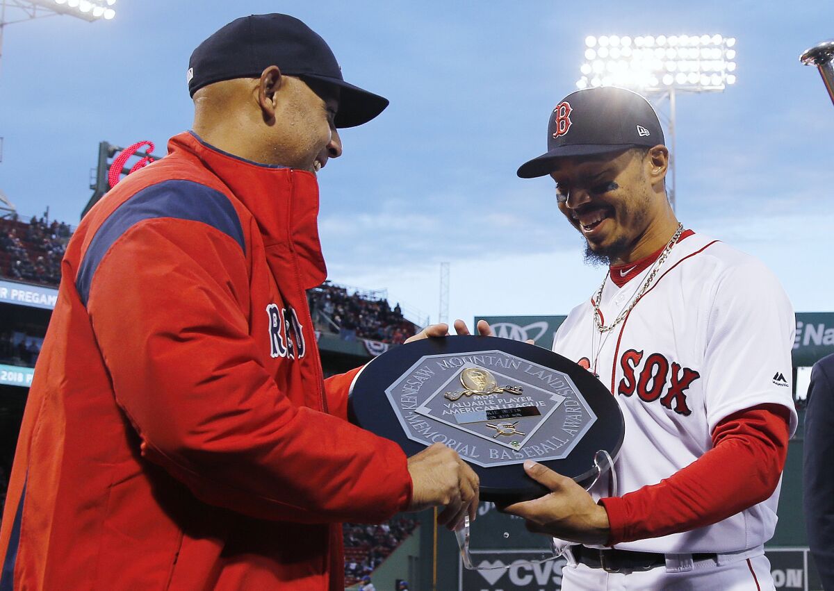 FILE - In this April 11, 2019, file photo, Boston Red Sox manager Alex Cora, left, presents right fielder Mookie Betts with the 2018 AL MVP Award before a baseball game between the Red Sox and the Toronto Blue Jays at Fenway Park in Boston. The award includes the name and image of Kenesaw Mountain Landis. (AP Photo/Winslow Townson, File)