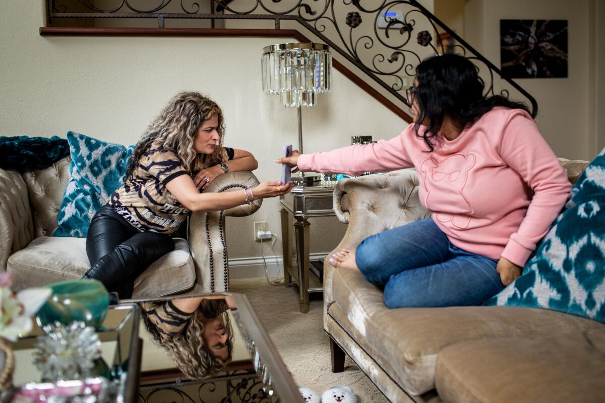 Laguna Niguel, California - May 23: Shashi Singh, wife of Dr. Pradyuman Singh, reviews a delivery food order with her daughter Elena, 22, at home in Laguna Niguel, CA, Tuesday, May 23, 2023. Dr. Singh, left the U.S. to help his mother in India in March 2020 and has been trying to get his immigration status reviewed since. The family only gets to interact with their father via Facetime, with his son, Anirudh, 12, the only U.S. citizen in the family, who can cross the border to visit him in Tijuana, Mexico. (Jay L. Clendenin / Los Angeles Times)