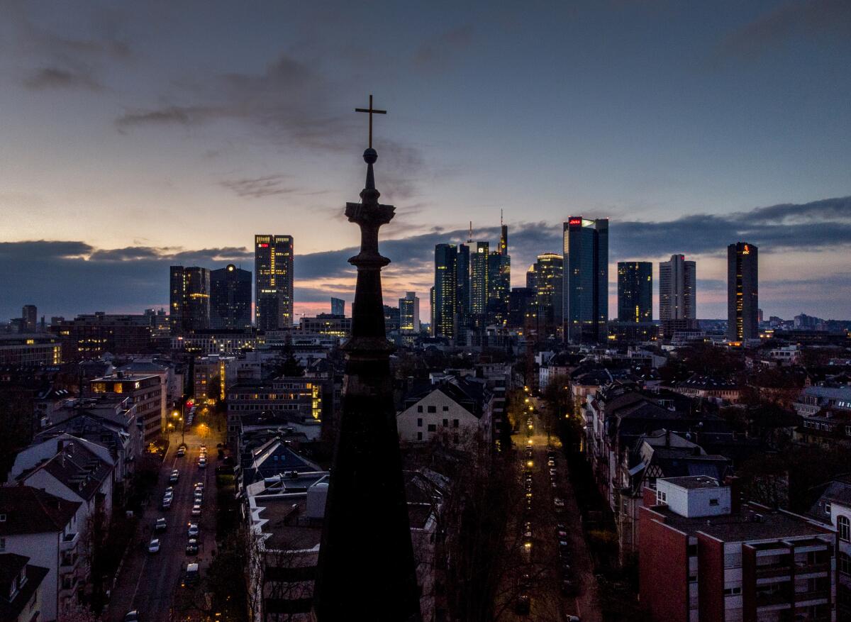 The buildings of the banking district stand behind a cross on top of a church in Frankfurt, Germany, on Good Friday, April 2, 2021. For a second year running the COVID-19 pandemic had a major effect on global celebrations of the Easter Holy Week. Many services were held outdoors or behind closed doors, but despite these restrictions the faithful found ways to mark one of the most important times in the Christian calendar. (AP Photo/Michael Probst)