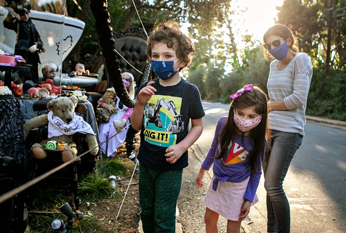 A family wears face coverings Wednesday while visiting a Brentwood home that goes all out with Halloween decorations.