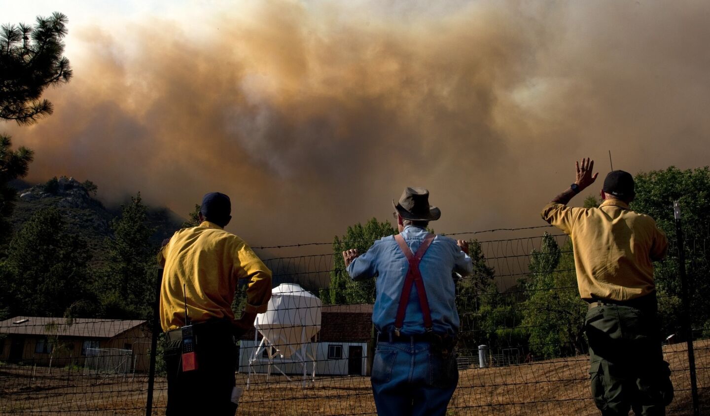 Resident Art Jaenke of Garner Valley, middle, watches the approaching Mountain fire with U.S. Forest Service firefighters Matt Boss, left, and Josh Richardson, near Highway 74 on July 17. Residents were told to evacuate, but Jaenke stayed behind to protect his property.