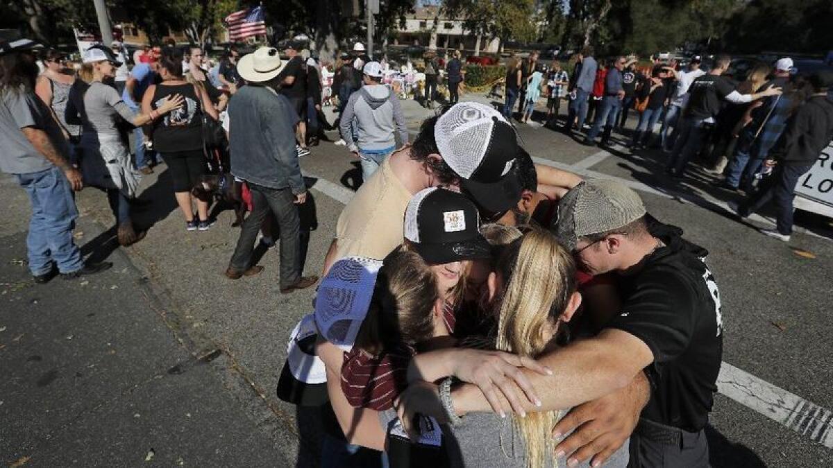 People huddle outside near a makeshift memorial.