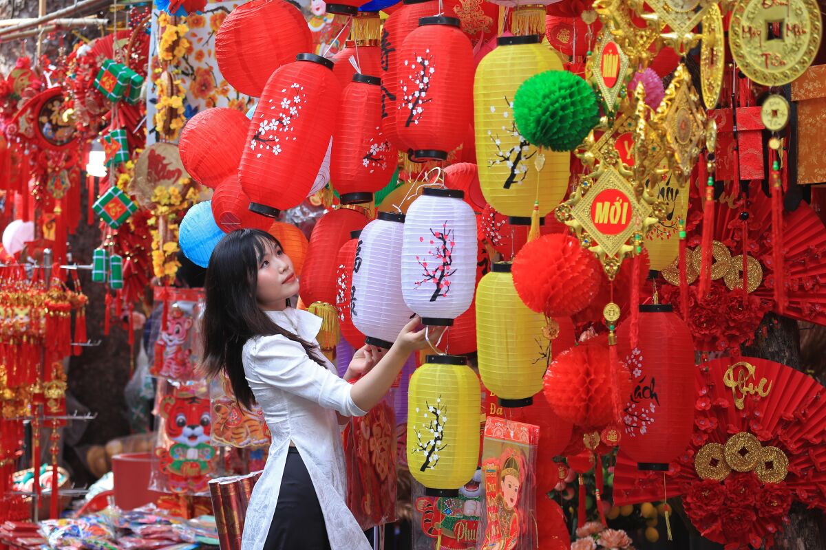 A woman looks at lanterns at the traditional Lunar New Year Tet market in the old quarter of Hanoi, Vietnam, in 2022.