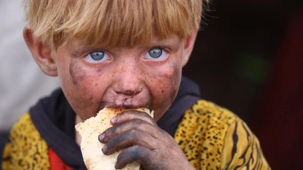 A displaced Syrian child, who fled the countryside surrounding the Islamic State group stronghold of Raqqa, eats at a temporary camp in the village of Ain Issa on May 2, 2017.