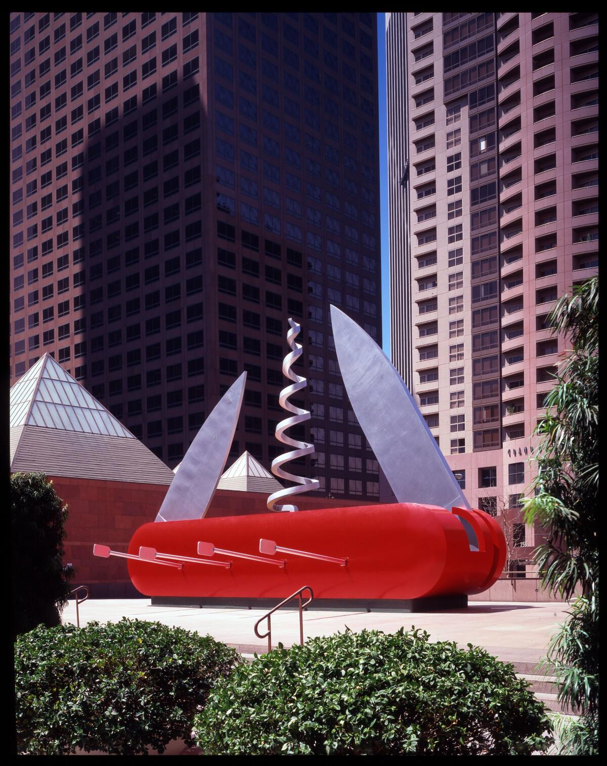 A sculpture resembling a boat made from a Swiss army knife stands in a plaza.