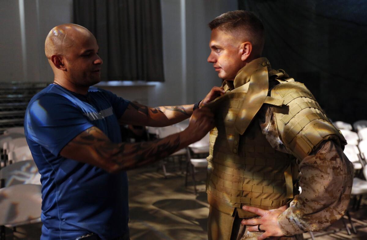 Former Marine Christian Ellis, left, fixes actor Todd Strange's vest before rehearsals of the opera "Fallujah," based on Ellis' experiences.