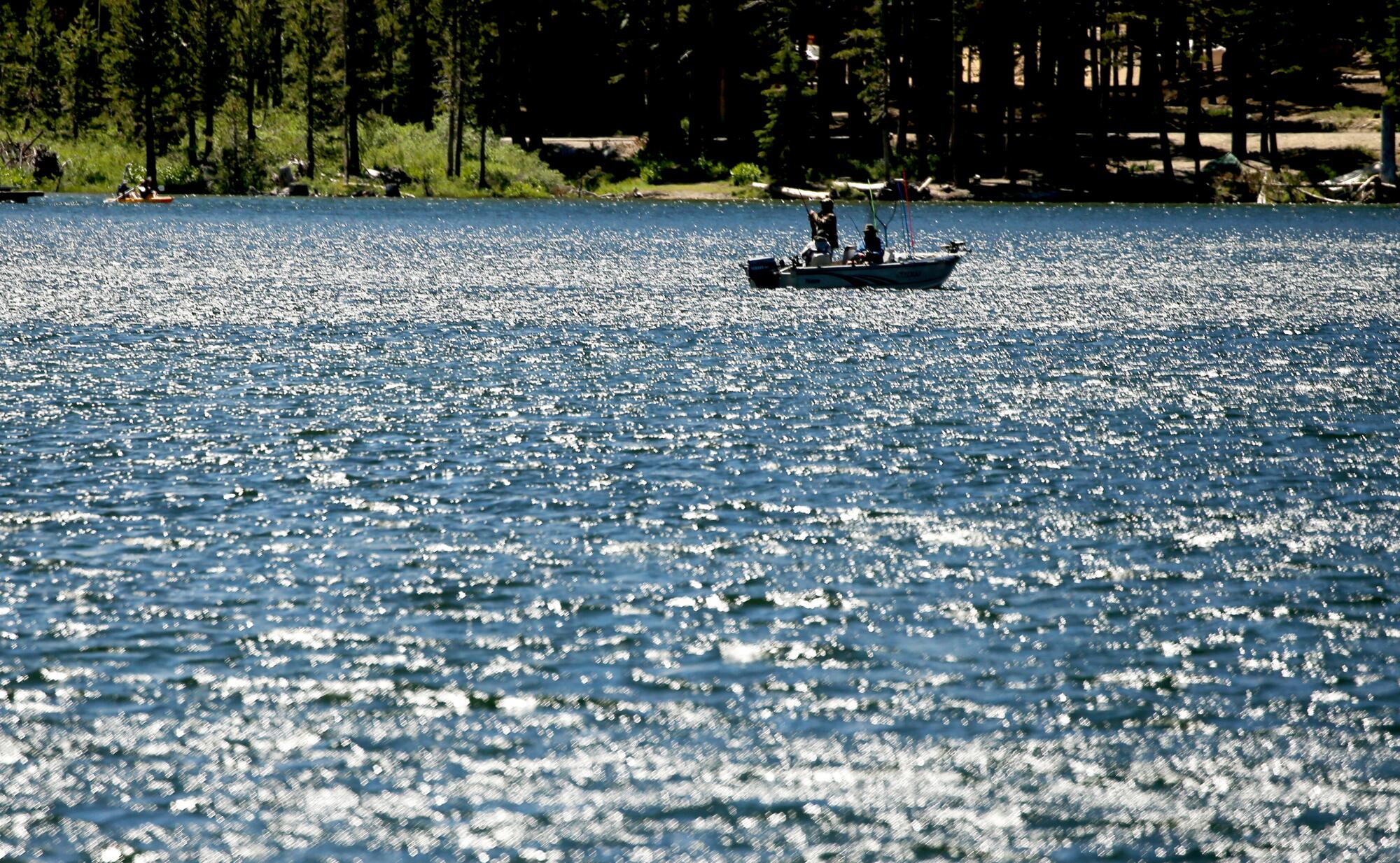 Anglers in a small motorboat cast lines into a bright blue lake.
