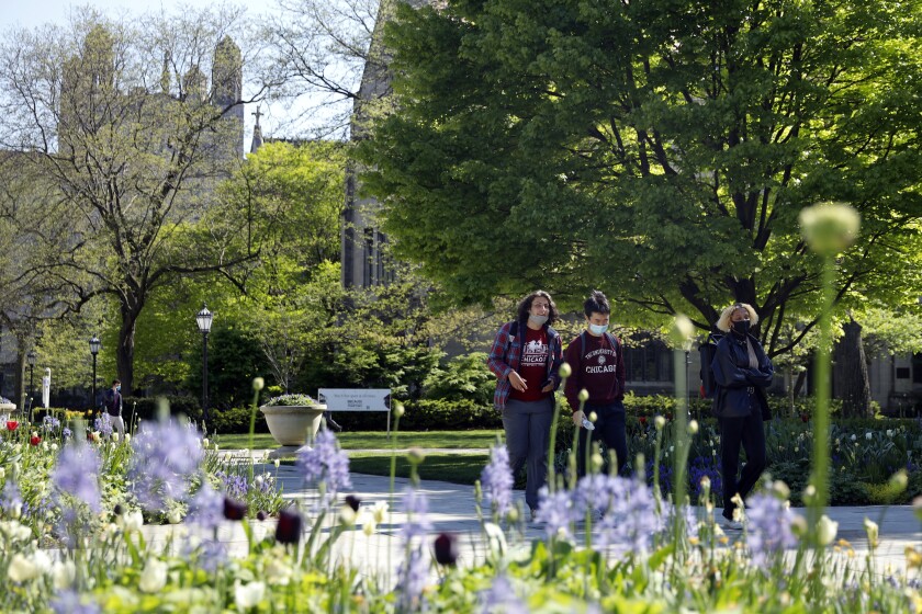 Students wearing masks make their way through the University of Chicago campus, Thursday, May 6, 2021, in Chicago. Even as restrictions relax across much of the United States, colleges and universities have taken new steps to police campus life as the virus spreads through students who are among the last adults to get access to vaccines. (AP Photo/Shafkat Anowar)