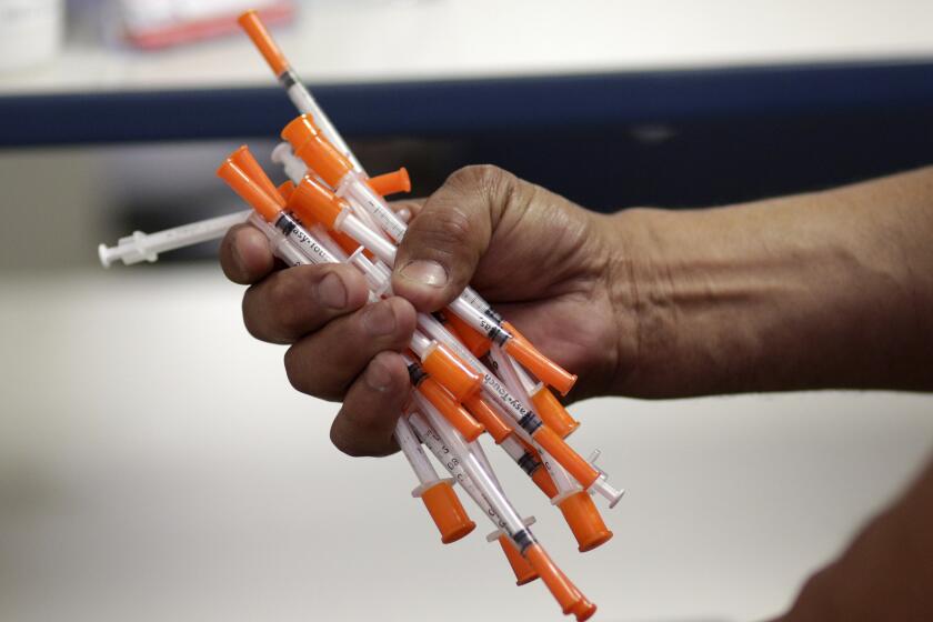 In this Monday, May 6, 2019 photo, Jose Garcia, an injection drug user, deposits used needles into a container at the IDEA exchange, in Miami. The University of Miami pilot program allows users to exchange used syringes for clean ones in order to avoid the transmission of HIV, Hepatitis C and other blood-borne diseases. Needle exchanges could eventually come to other parts of the state under a new law signed by Gov. Ron DeSantis. (AP Photo/Lynne Sladky)