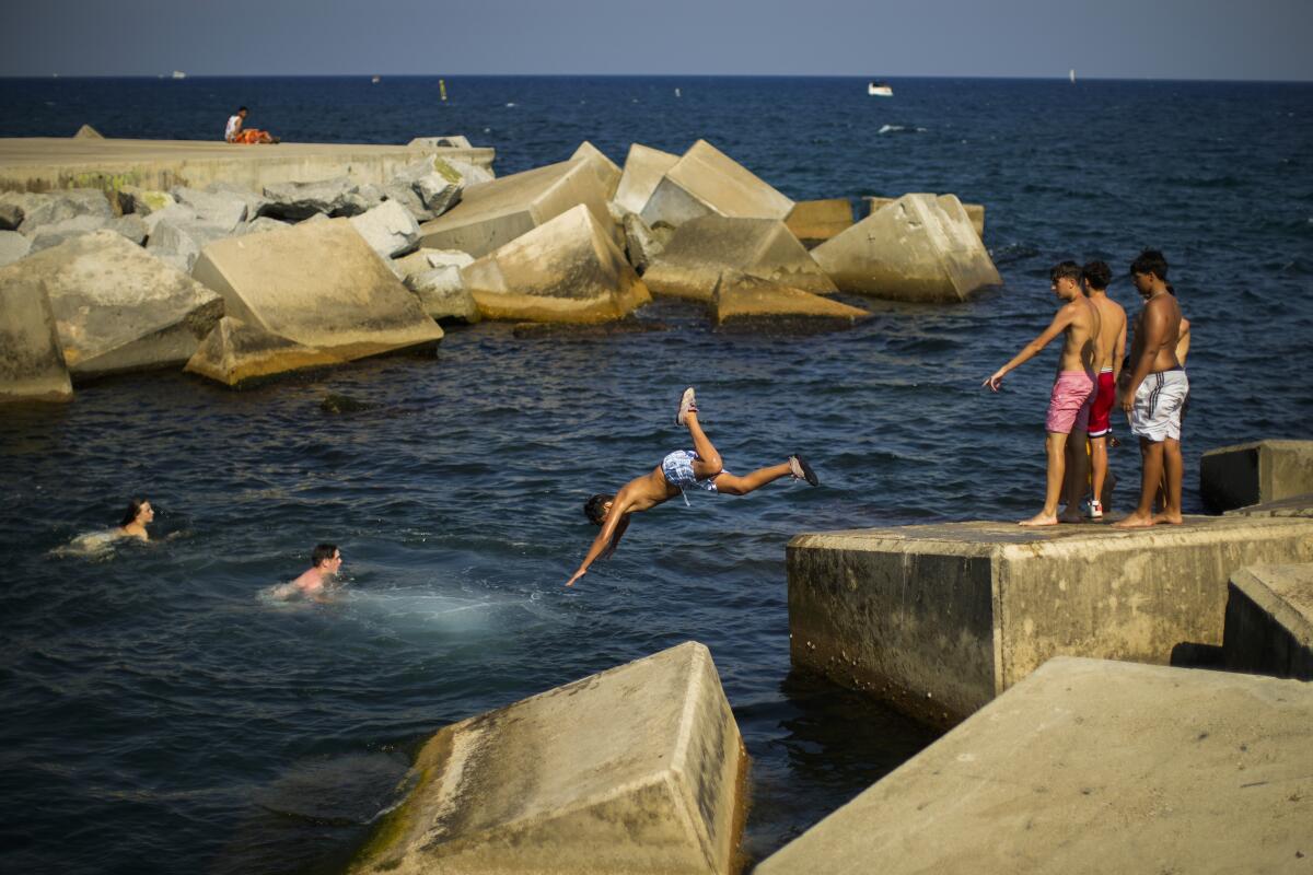 Youngsters dive into the Mediterranean sea during a hot sunny day in Barcelona, Spain, Thursday, July 21, 2022. (AP Photo/Francisco Seco)