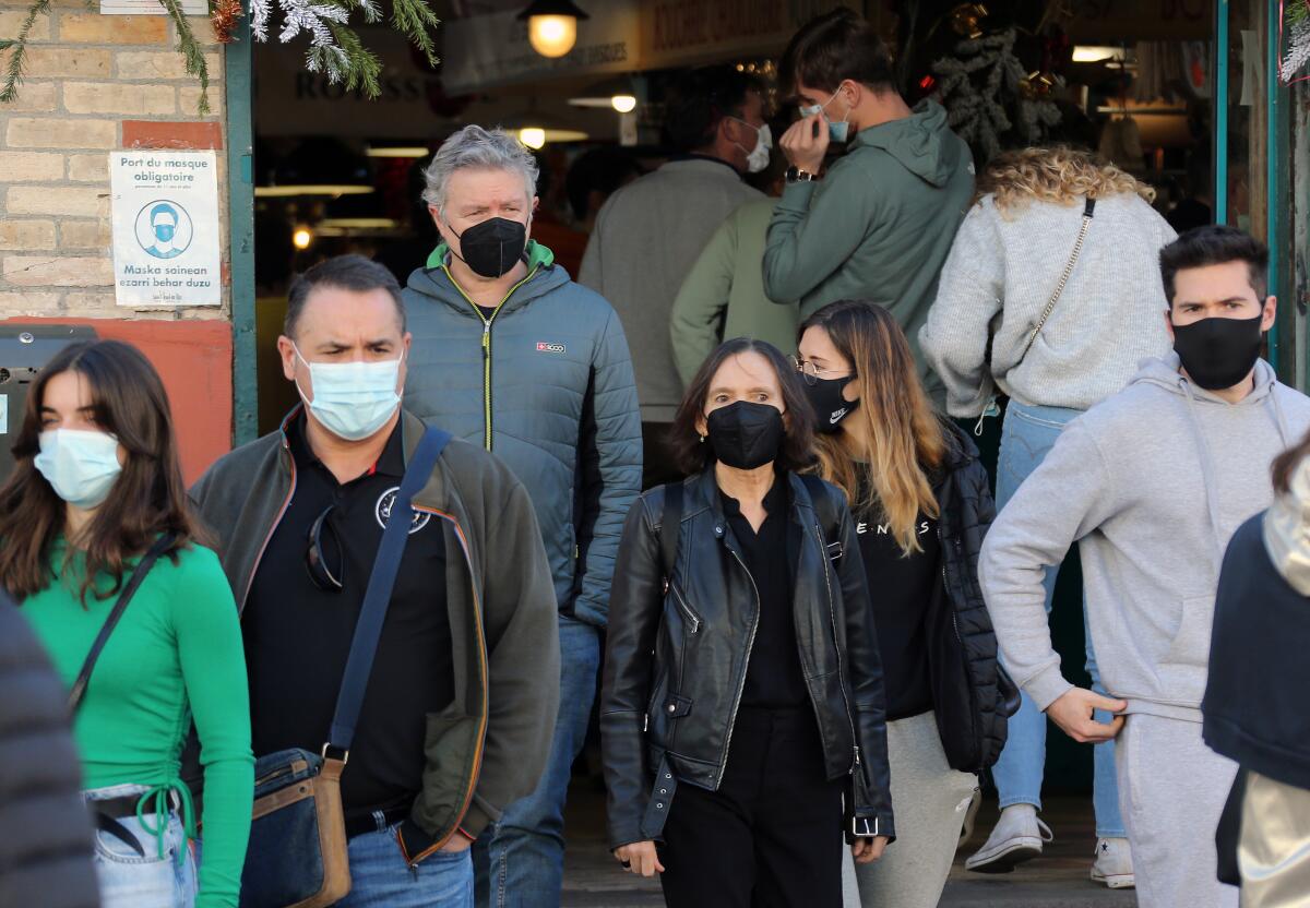 People wearing face masks walk on the street in Saint Jean de Luz, southwestern France.
