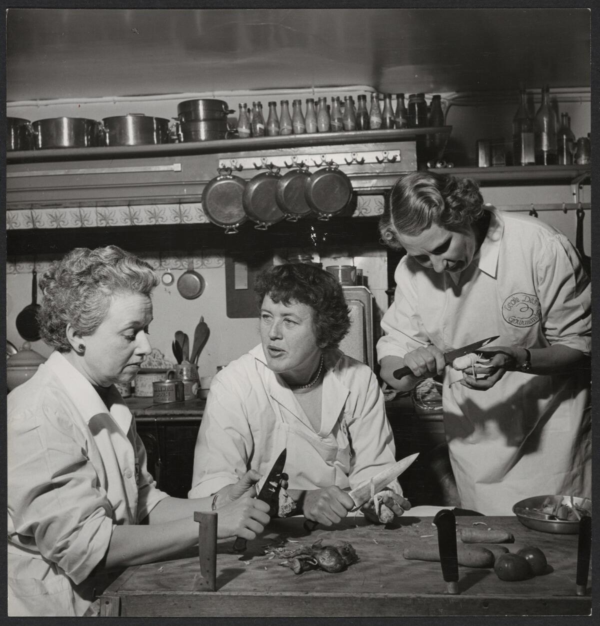 Julia Child peels vegetables with with collaborators Simone Beck and Louisette Bertholle. 