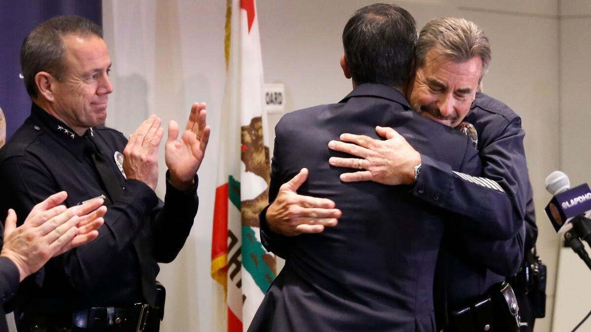 LAPD Chief Charlie Beck, right, and Mayor Eric Garcetti embrace at a news conference Friday where Beck announced he will retire in June. At left is Assistant Chief Michel Moore.