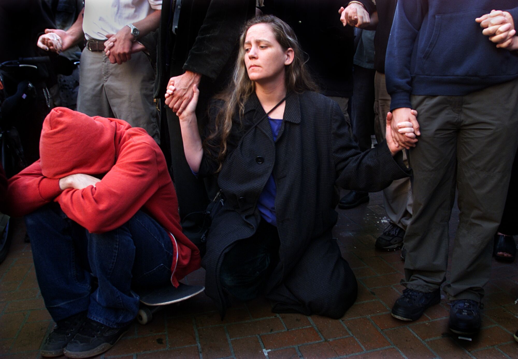 A group of people join hands, including a kneeling woman