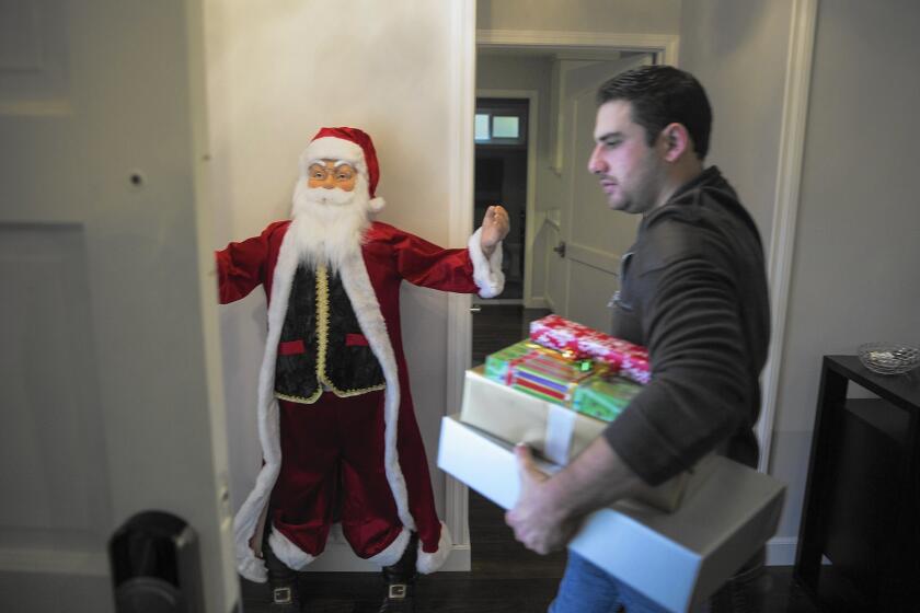 Peter Rabadi carries Christmas gifts out of his home in Porter Ranch. He and his wife, Danielle, will be staying with relatives until the leak from a nearby Southern California Gas Co. well is fixed.