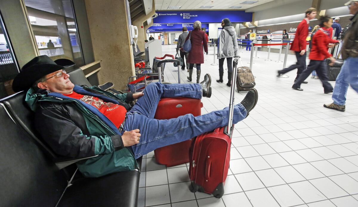 David McCain of Abilene, Texas, relaxes in the seats of the ticketing area for American Airlines in Terminal C at Dallas-Fort Worth Airport after his flight home was canceled. A cold front began to move into the North Texas area Sunday, which could affect Thanksgiving travel as it heads east.