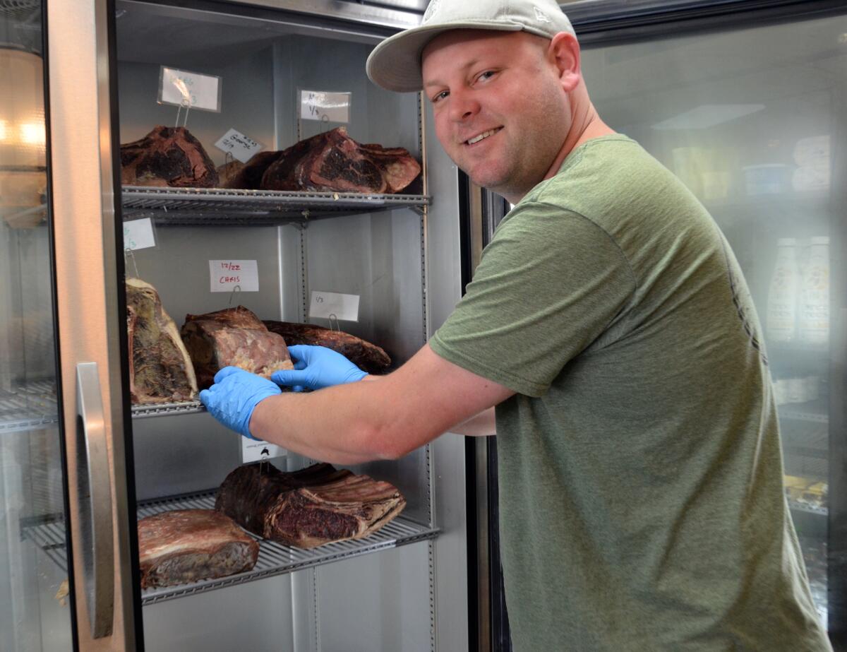 Sections Fine Meats owner Ryan Ramming stands with fresh prime rib dry aging in a special locker.