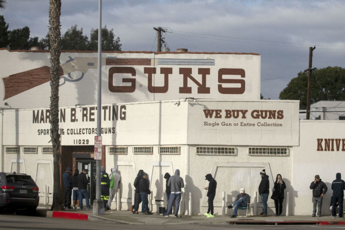People line up down the sidewalk and around the corner outside a gun store.