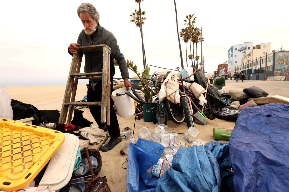 A man gathers belongings at a camp on the beach