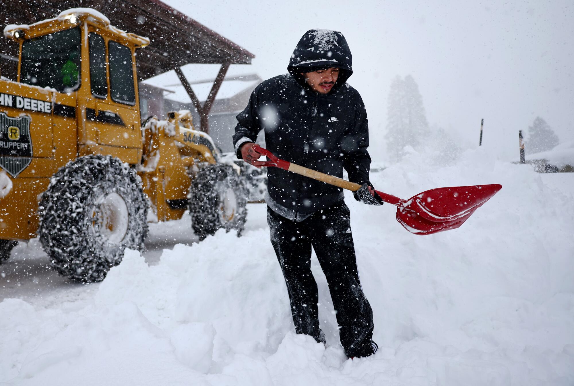 Luis Apolinar attempts to dig out his vehicle as snow falls.