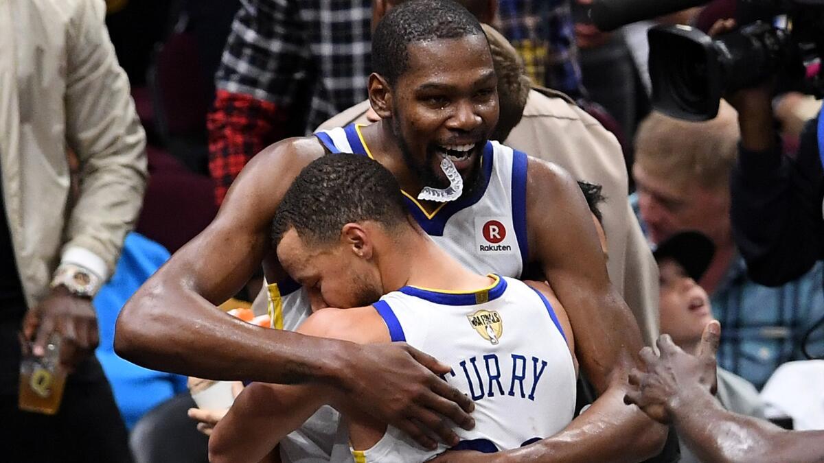 Warriors All-Stars Stephen Curry and Kevin Durant embrace after winning the NBA title on Friday night in Cleveland.