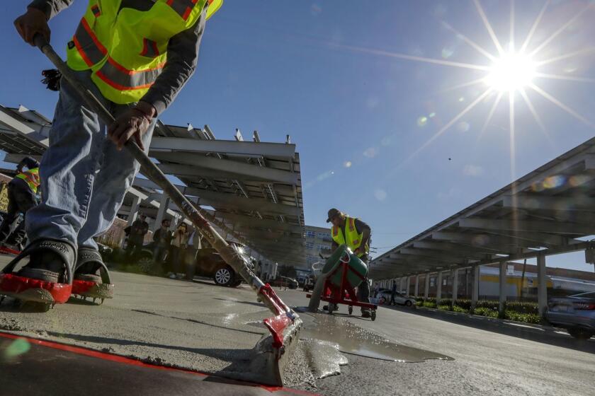 LOS ANGELES, CA, MARCH 30, 2019 --- Juan Reyes, left, and Devin Vestal apply a polymer based pavement coating by ePAVE, one of four sealcoatings being tested, on a section LKIC parking. The Los Angeles Cleantech Incubator (LACI) along with its key partners; the Los Angeles Bureau of Street Services, The Los Angeles Department of Water and Power (LADWP), and Climate Resolve, performed a unique ?Cool Pave? pilot project. (Irfan Khan / Los Angeles Times)