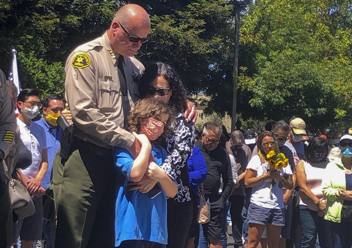 Santa Cruz County Sheriff Jim Hart stands with his wife and child as people pay their respects to Sgt. Damon Gutzwiller.