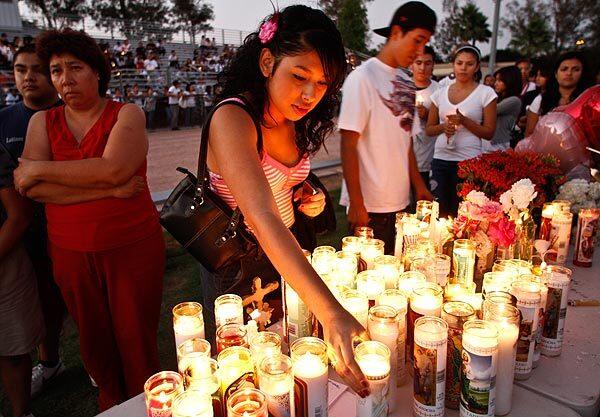 Mourners place candles on a table during the vigil for slaying victim Norma Lopez, who vanished last Thursday. See full story