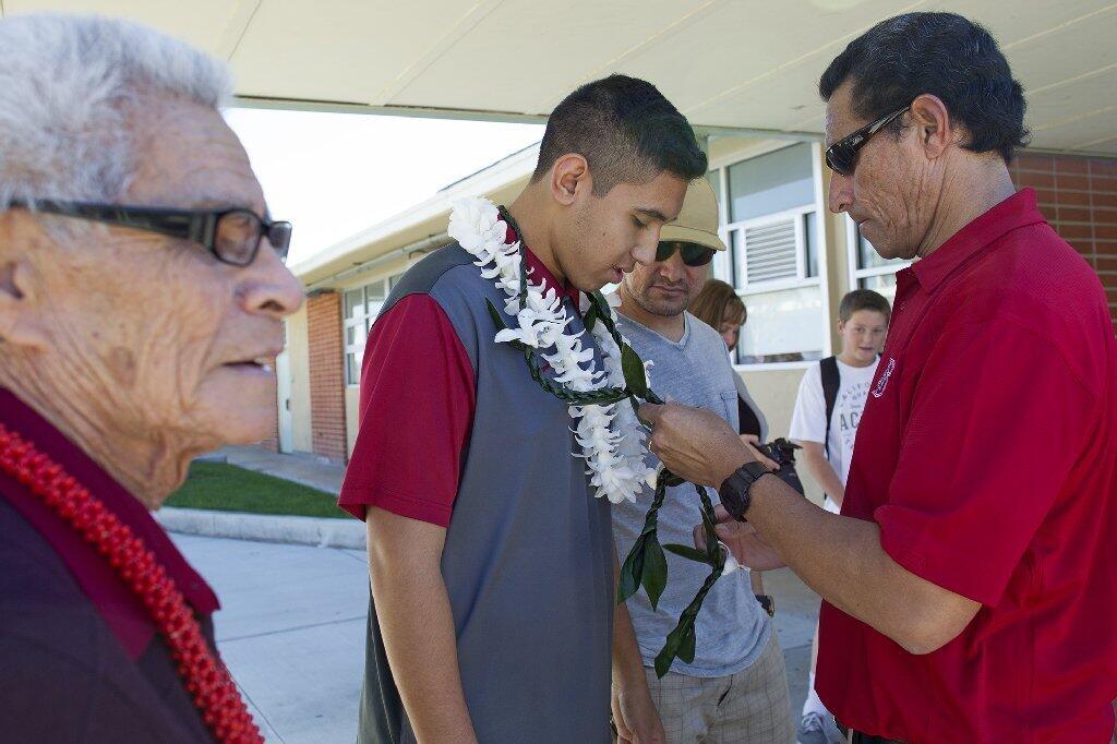 Costa Mesa High senior volleyball standout Mason Tufuga, center, looks on as his father Mai, right, fixes a lei around his neck before signing his intent to attend Stanford University.