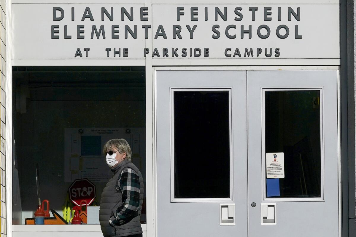 A pedestrian walks below a sign for Dianne Feinstein Elementary School 