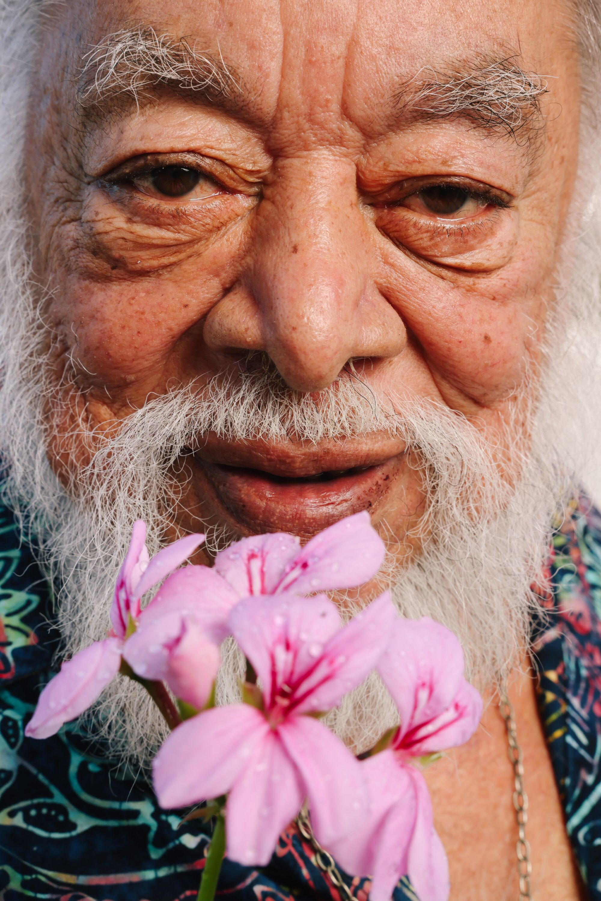 A close up of a man's face holding a flower.
