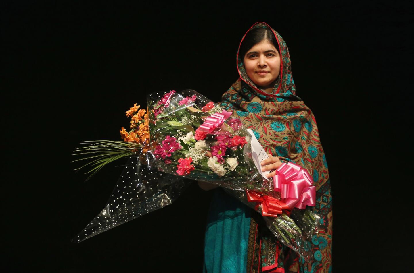 Malala Yousafzai holds a bouquet of flowers, given to her on behalf of the Pakistani Prime Minster during a press conference at the Library of Birmingham after being announced as a recipient of the Nobel Peace Prize, on October 10, 2014 in Birmingham, England.