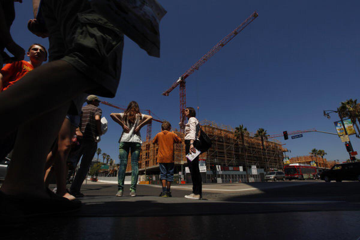 Anja Heimann and her fiance's children Ben Heidenreich, 9, and Emily Heidenreich, 13, wait to cross the road near where construction takes place at the intersection of Hollywood and Argyle in Los Angeles.