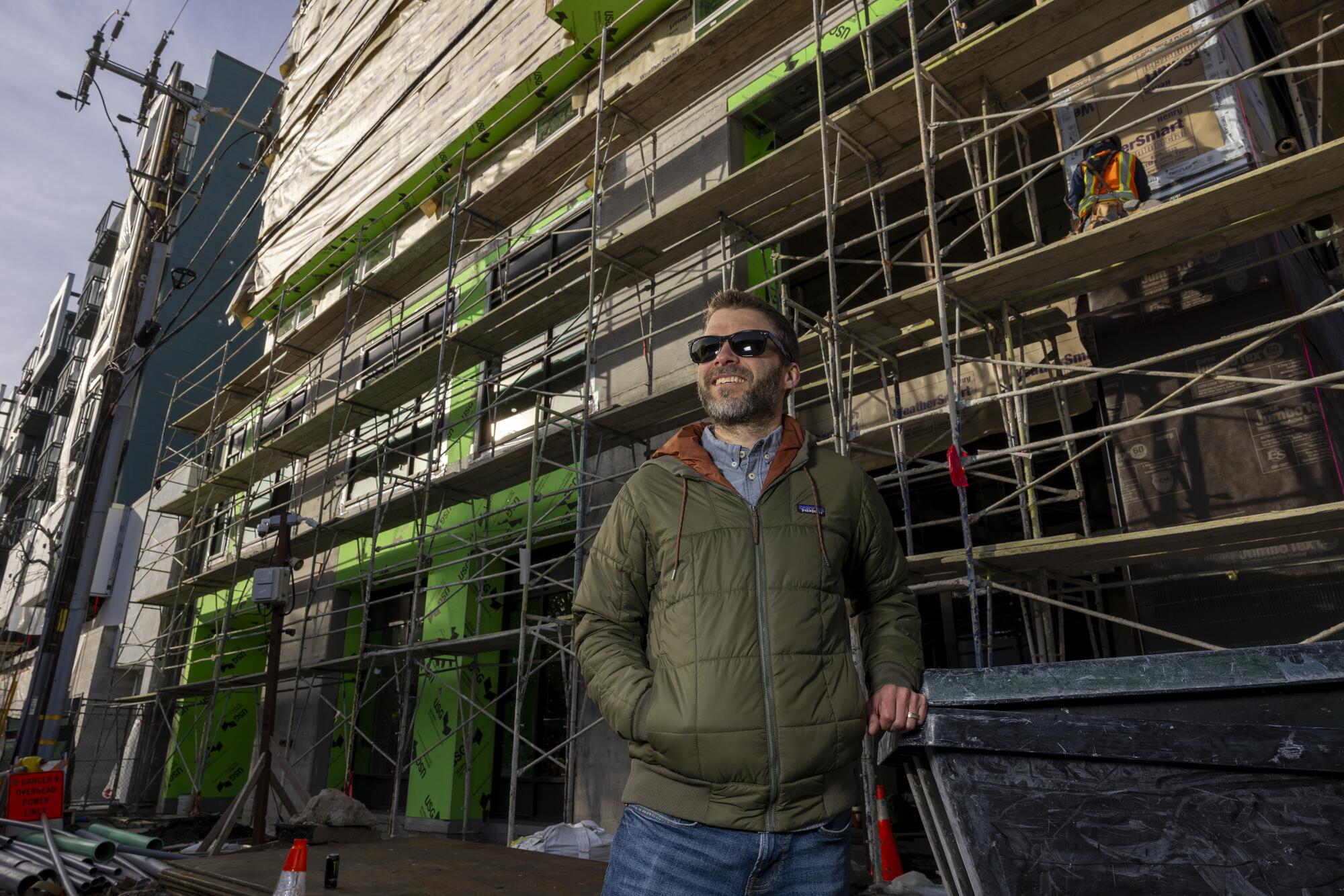 Lee Butler stands in front of a construction site.